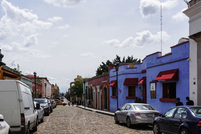 Cars on street amidst buildings in city against sky