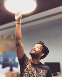 Man touching illuminated pendant light at home