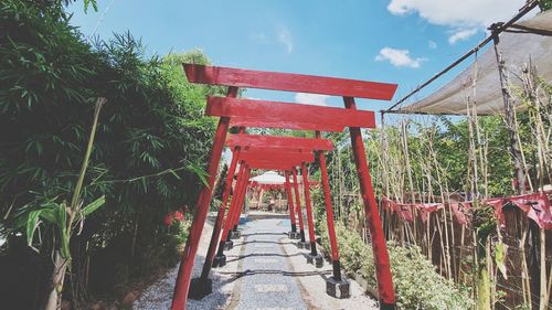 Red wooden structure amidst plants against sky