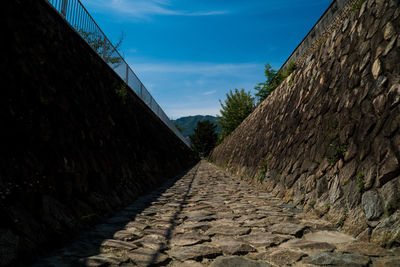 Footpath amidst wall against sky