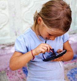 Girl using smart phone against wall at home