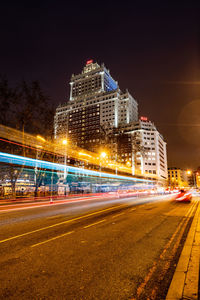 Light trails on city street by buildings at night