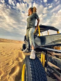 Full length of woman standing on beach buggy at desert