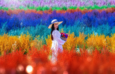 Full length of woman standing by multi colored flower in field