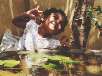 Smiling boy holding tree trunk