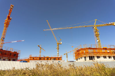 Low angle view of crane against clear blue sky