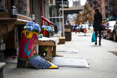 Person sitting on footpath by street in city