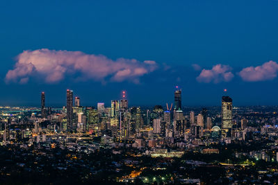 Illuminated buildings in city against blue sky