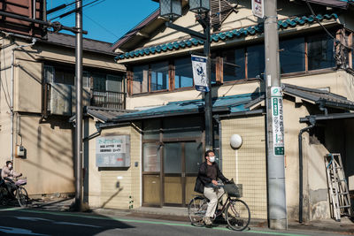 Man riding motor scooter on street against buildings