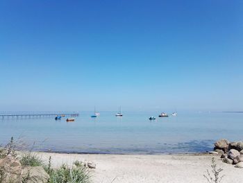 Sailboats in sea against clear blue sky