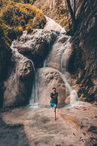 Full length of man standing by waterfall