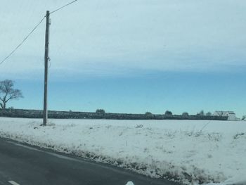 Road by sea against sky during winter