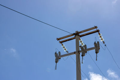 Low angle view of old overhead power line against blue sky