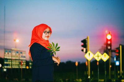 Close-up of young woman standing against illuminated sky at night