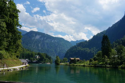 Scenic view of lake by mountains against cloudy sky