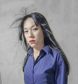 Portrait of beautiful young woman standing against wall