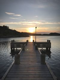 Pier over sea against sky during sunset