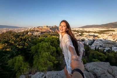 Portrait of smiling woman standing on mountain against sky