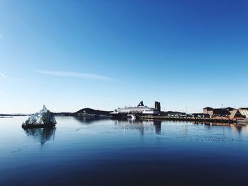 Scenic view of river by building against clear blue sky