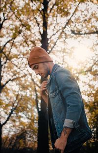 Low angle view of man standing by tree autumn warm