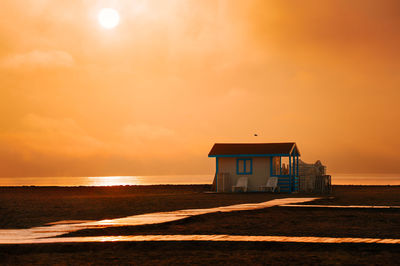 Beach cabin on shore at misty sunrise