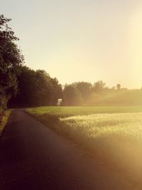 Road amidst field against clear sky