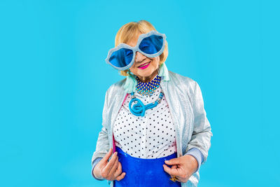 Portrait of woman wearing sunglasses against blue background