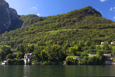 Scenic view of tree mountain by lake como against blue sky