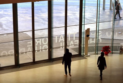 Rear view of people walking by sea