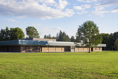 Trees and houses on field against sky