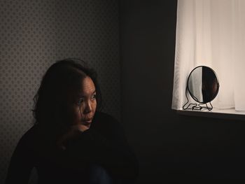 Woman with reflection in mirror sitting at home