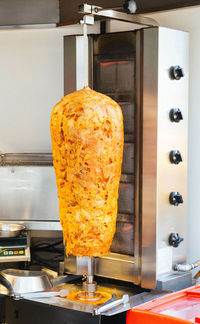 Close-up of chicken kebab on gyro rotisserie in restaurant kitchen