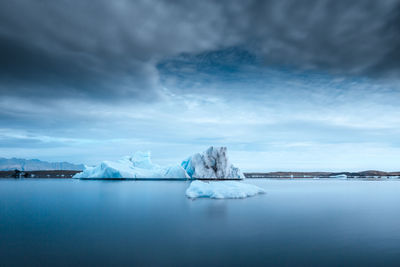 Iceberg floating in sea against sky at dusk