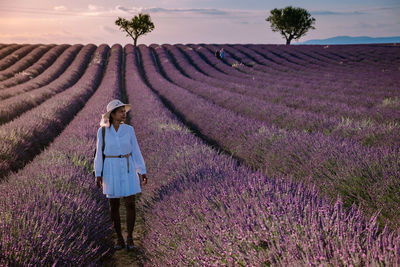 Woman standing by purple flower on field