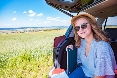 Portrait of smiling young woman sitting on field