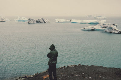 Rear view of man and woman standing on frozen sea