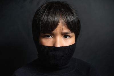 Close-up portrait of woman covering face against black background