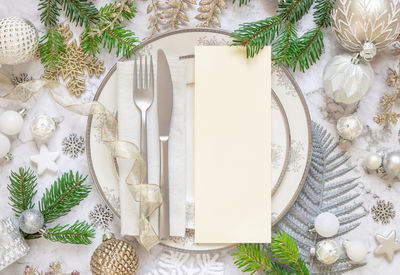 Festive table setting with a card, ornaments and fir tree branches top view