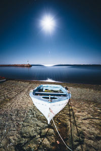 Boat moored on beach against clear blue sky