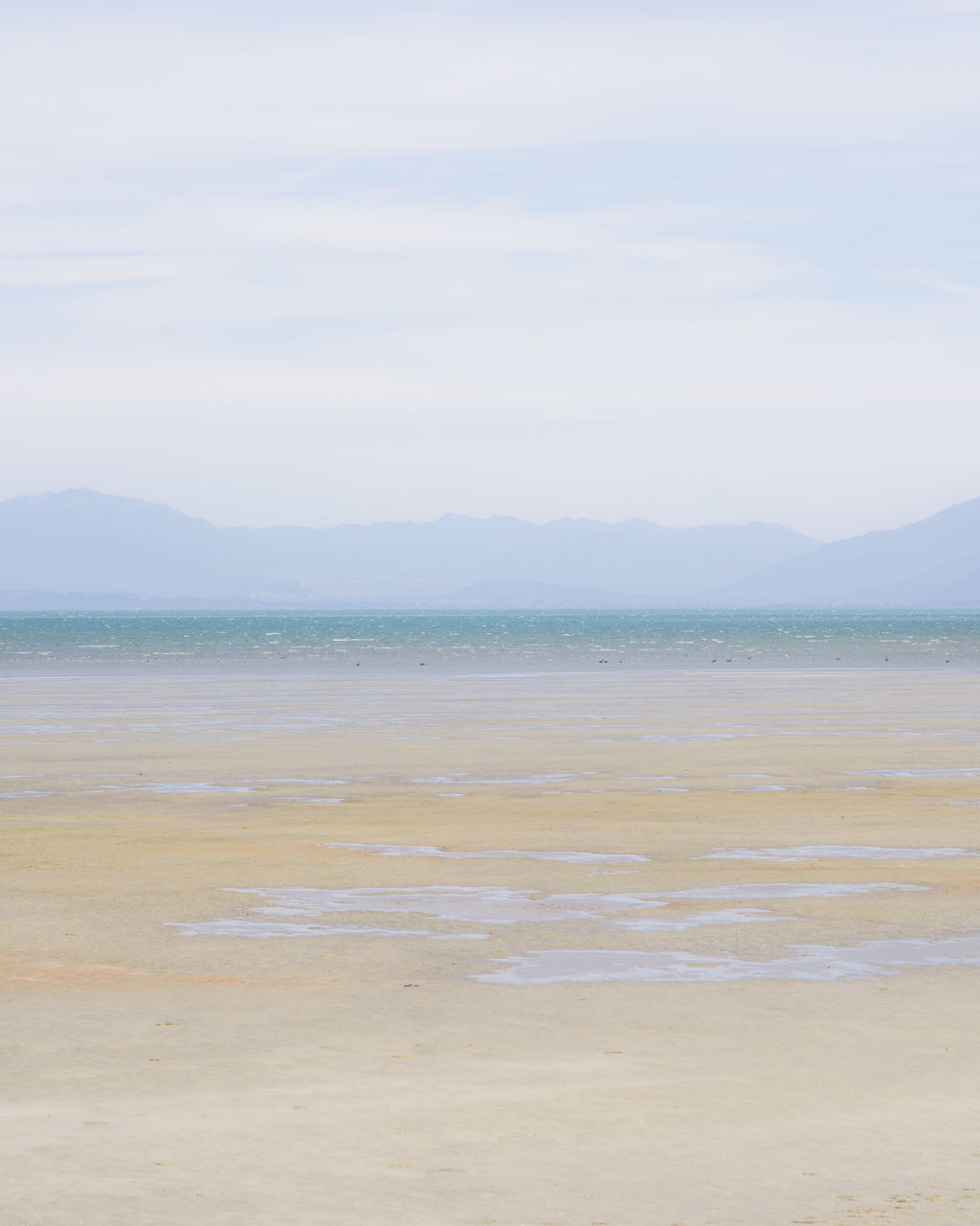 water, beach, sea, tranquil scene, mountain, tranquility, scenics, sky, sand, beauty in nature, shore, nature, idyllic, mountain range, coastline, day, remote, outdoors, non-urban scene, cloud - sky