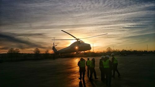 Silhouette of men in city against sky during sunset