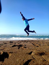 Full length of man jumping over sea against clear sky