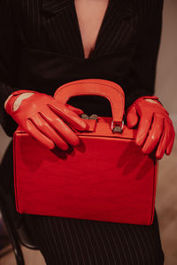 Female hands in a leather gloves holding a classic bright red handbag. fashion shot. vertical