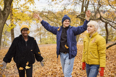 Happy young friends throwing autumn leaves