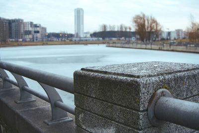 Close-up of hand by railing against river in city