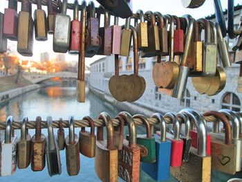 Close-up of padlocks hanging on railings over river