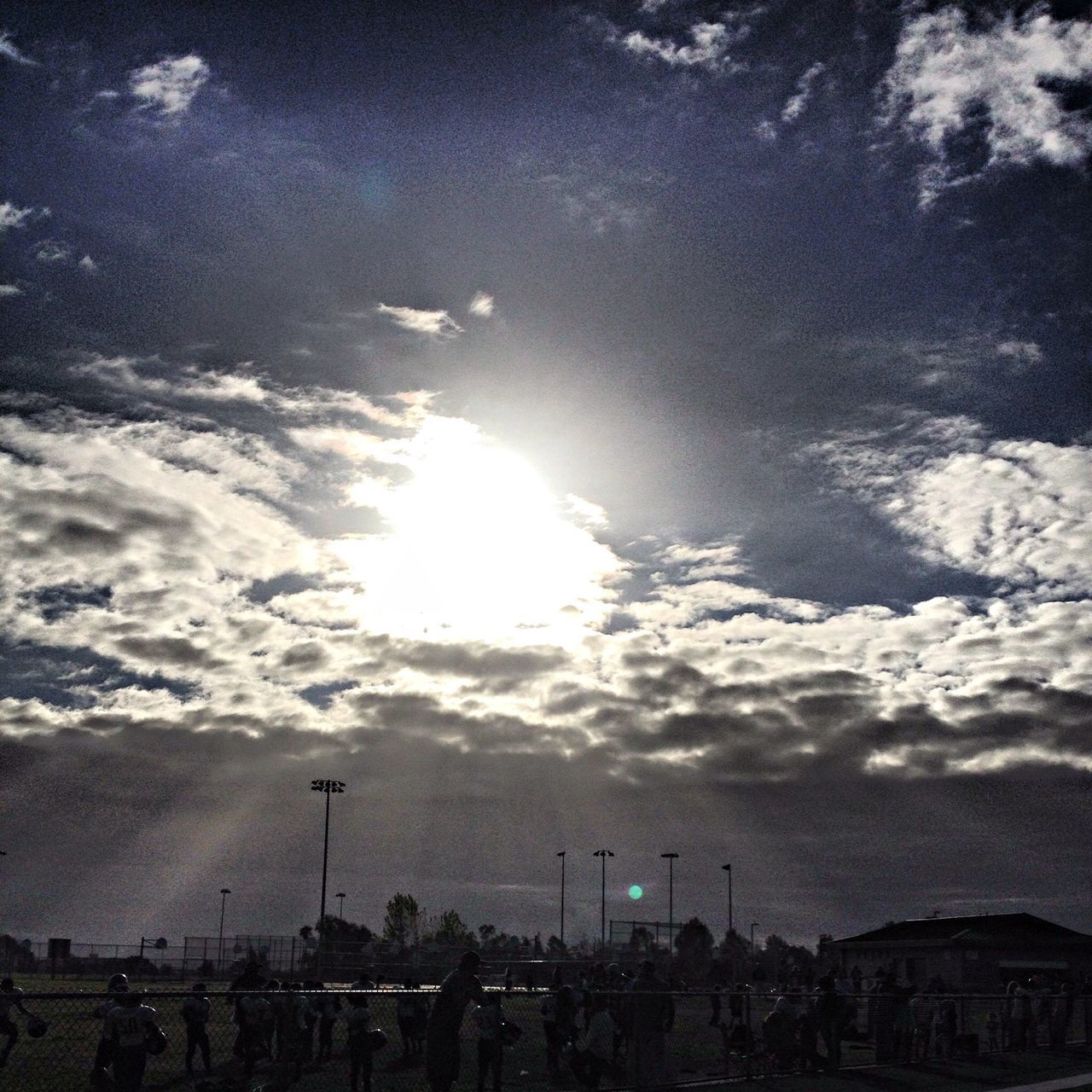 sky, sun, cloud - sky, sunbeam, silhouette, sunlight, scenics, beauty in nature, cloudy, cloud, tranquil scene, nature, tranquility, sunset, lens flare, outdoors, idyllic, low angle view, building exterior, built structure