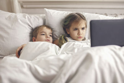 Siblings watching video in mobile devices in bed, gadget dependence and addiction, online lifestyle