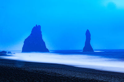 Rock formations on beach against blue sky