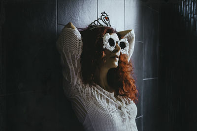 Woman wearing novelty glasses while leaning on wall